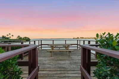 Scenic boardwalk leading to a peaceful waterfront deck with sunset views. Enjoy dining, relaxing, or simply watching the sky glow over calm coastal waters.