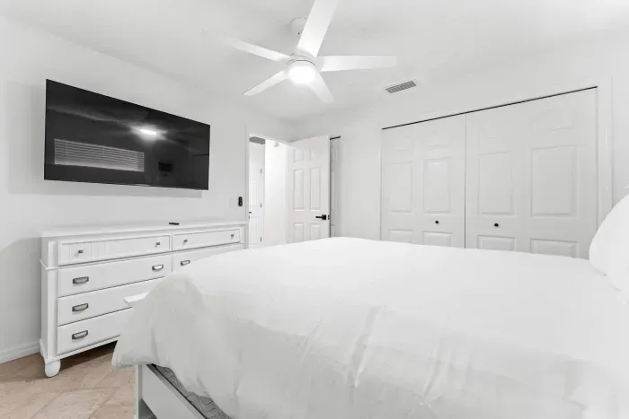 Relax in a peaceful space featuring a cozy bed, TV, and plenty of storage — the perfect retreat to unwind after a fun day at the beach.