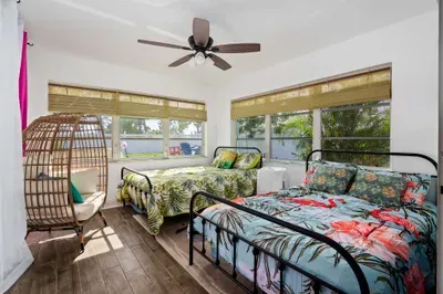 This bright and breezy bedroom is perfect for groups or families, featuring two comfy full-size beds with tropical-themed bedding and garden views from every window.