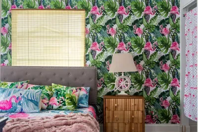 Sleep in style in this tropical-themed bedroom that radiates charm and vacation vibes! With bold flamingo wallpaper, leafy botanical accents, and vibrant bedding, this space is a true escape.