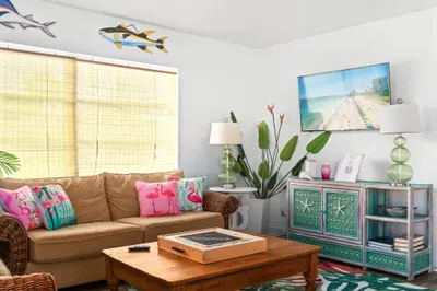 Sink into seaside comfort! This tropical-inspired space features playful pops of color, flamingo pillows, beachy decor, and a smart TV for laid-back movie nights.