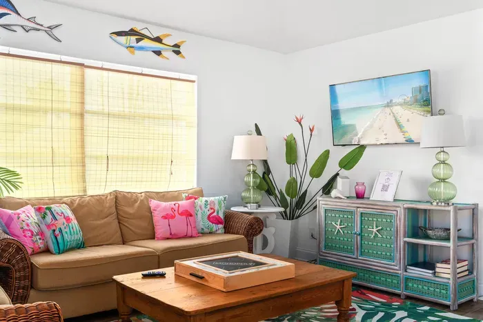 Sink into seaside comfort! This tropical-inspired space features playful pops of color, flamingo pillows, beachy decor, and a smart TV for laid-back movie nights.