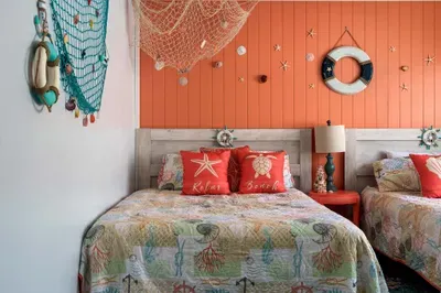 Drift off to sleep in this vibrant beach-themed bedroom, featuring two cozy beds adorned with sea-inspired linens and decor.
