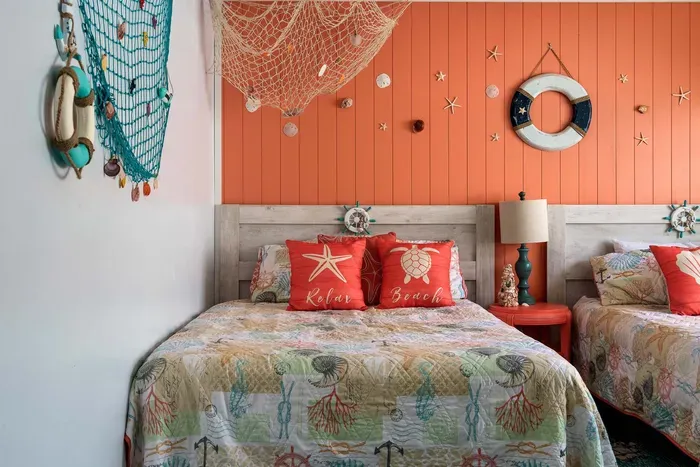 Drift off to sleep in this vibrant beach-themed bedroom, featuring two cozy beds adorned with sea-inspired linens and decor.