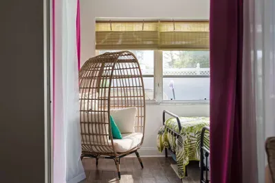 Unwind in our cozy, egg-shaped rattan chair nestled beside large, sun-filled windows. This inviting corner is perfect for morning coffee, afternoon reading, or simply soaking in the peaceful, tropical ambiance of the room