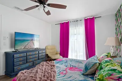 Wake up in paradise! This colorful, flamingo-inspired bedroom features bright pink accents, lush tropical bedding, and a stunning wallpaper that brings the outdoors in. Enjoy your favorite shows on the large flat-screen TV.