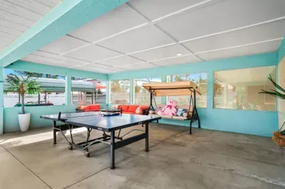 This sun-filled screened patio is where comfort meets coastal fun! Featuring a ping pong table for friendly competition, a cozy swing bench with plush toys for the kids, and a vibrant outdoor sofa perfect for group gatherings.