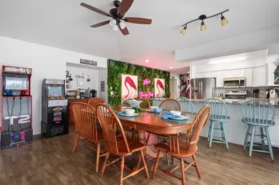 Step into a vibrant dining and entertainment space where fun meets Florida flair! Whether you're enjoying a family meal at the spacious wooden dining table or battling it out on the retro arcade machines, this space is designed for connection.