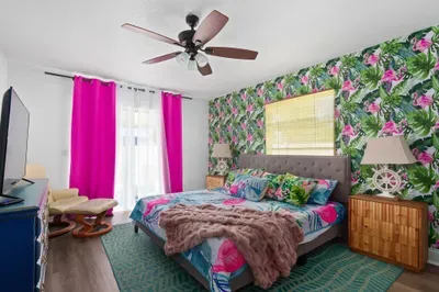 Drift off in paradise in this bold, island-inspired bedroom! Bursting with color and character, the space features a plush king-sized bed, eye-catching tropical wallpaper, and luxurious linens for ultimate comfort.