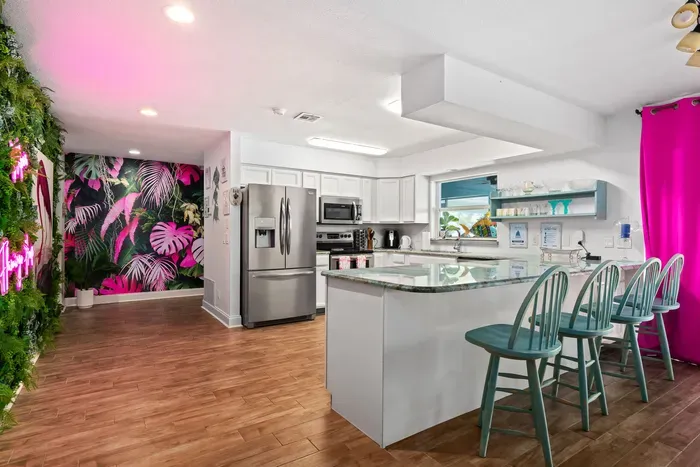 Whip up your favorite meals in this fully equipped, tropical-themed kitchen! Featuring stainless steel appliances, granite countertops, and a large island with seating for four, this space is both functional and fun.