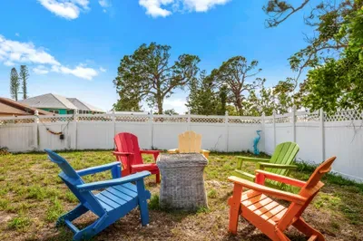 Gather around the charming firepit in this vibrant backyard retreat, complete with colorful Adirondack chairs and a fully fenced yard for privacy.