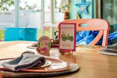 Start your day with sunshine and a smile at this colorful outdoor dining spot, bursting with beachy charm and cheeky décor. From the tropical-themed place settings to the fun flamingo signs, every detail adds a splash of vacation joy.