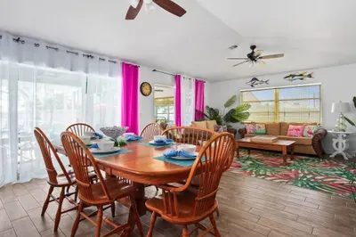 Host unforgettable meals and moments in this spacious, sun-soaked dining and lounge area! Enjoy home-cooked dinners around the large family-style table, then kick back in the vibrant tropical living room just steps away.