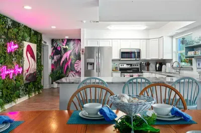 Dine in paradise! This vibrant kitchen and dining space combines functionality with flair—featuring a full-sized stainless steel kitchen, pristine white cabinetry, and open shelving stocked for your stay.