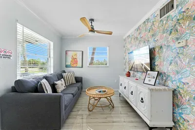 Bright and cheerful living room with a colorful accent wall, comfy gray sofa, and coastal-inspired décor. Enjoy streaming your favorites on the flat-screen TV or relaxing as sunlight fills this inviting space.