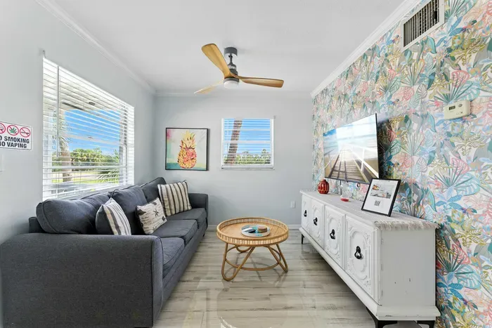 Bright and cheerful living room with a colorful accent wall, comfy gray sofa, and coastal-inspired décor. Enjoy streaming your favorites on the flat-screen TV or relaxing as sunlight fills this inviting space.
