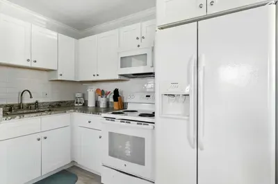 Bright, fully equipped kitchen with sleek white cabinetry, modern appliances, and granite countertops. Perfect for cooking up your favorite meals while enjoying the clean, fresh coastal vibe of your getaway.