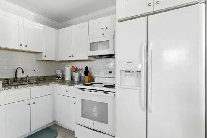 Bright, fully equipped kitchen with sleek white cabinetry, modern appliances, and granite countertops. Perfect for cooking up your favorite meals while enjoying the clean, fresh coastal vibe of your getaway.