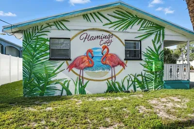 Standout curb appeal with a vibrant 'Flamingo Cay' mural featuring tropical leaves and bright pink flamingos by the sea. This eye-catching exterior sets the stage for a colorful and unforgettable coastal getaway.