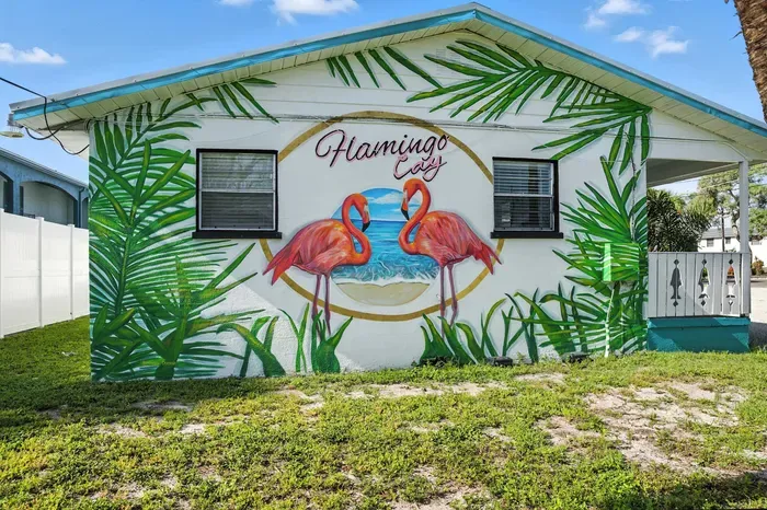 Standout curb appeal with a vibrant 'Flamingo Cay' mural featuring tropical leaves and bright pink flamingos by the sea. This eye-catching exterior sets the stage for a colorful and unforgettable coastal getaway.