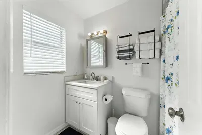 Bright and fresh bathroom with a clean white vanity, modern fixtures, and soft natural light. Thoughtful touches like plush towels and a hint of floral charm create a welcoming space to refresh and unwind.