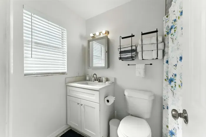 Bright and fresh bathroom with a clean white vanity, modern fixtures, and soft natural light. Thoughtful touches like plush towels and a hint of floral charm create a welcoming space to refresh and unwind.
