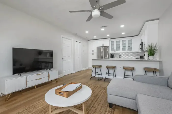 Open-concept living area with cozy sectional, large smart TV, and sleek kitchen views. Enjoy modern décor, warm lighting, and a relaxing vibe—perfect for lounging or entertaining after a day of exploring.
