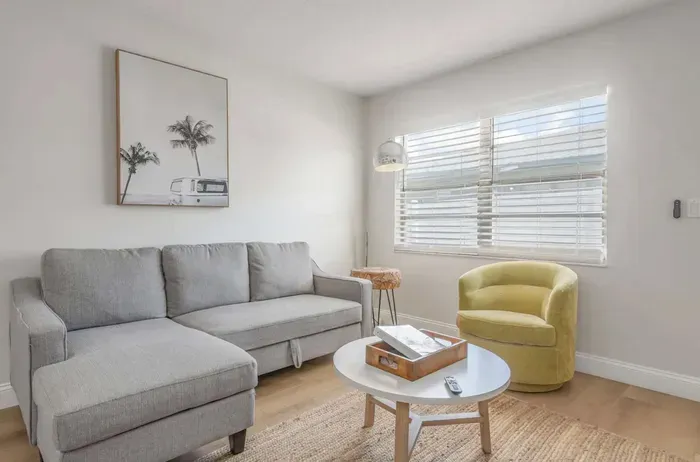 Cozy and sunlit living room featuring a plush sectional, modern décor, and stylish accent chair. Relax with natural light streaming in, perfect for unwinding or enjoying a quiet morning coffee.