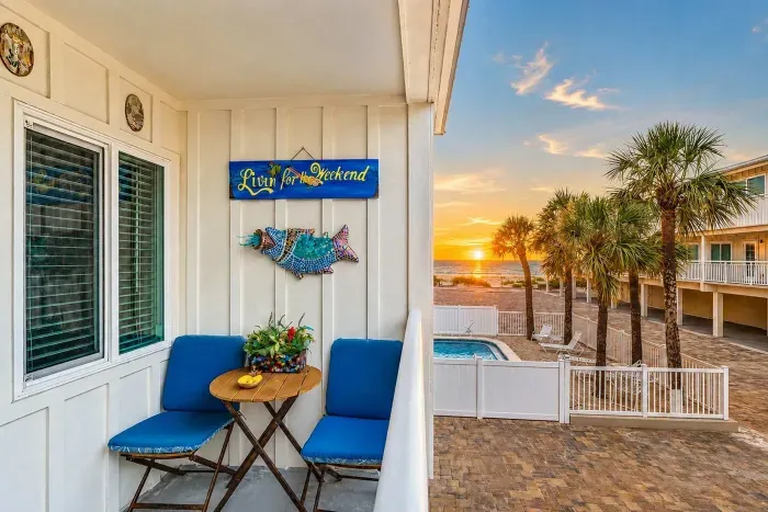 The balcony. Sunset over the Gulf, pool below, palm shadows, and a seat waiting. This is the payoff for a slow day.