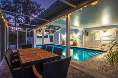 Relax in this stylish backyard oasis featuring a private pool, covered patio, and outdoor dining under warm string lights. Perfect for evening swims, alfresco meals, and unforgettable nights in a serene, resort-style setting.