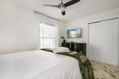 Relax in this bright, comfortable bedroom featuring a plush bed, smart TV, and soothing décor. Natural light fills the space, creating a peaceful retreat perfect for unwinding, streaming your favorites, and enjoying a restful night’s sleep.