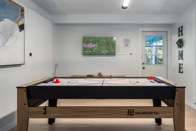 Challenge friends in the game room featuring a sleek shuffleboard table. Perfect for game nights, friendly competition, and relaxing indoors, comfort to your stay.