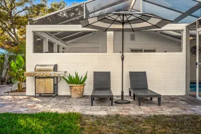 Relax on the sun loungers beside the screened patio, complete with grill and umbrella shade. Perfect for soaking up the sun, enjoying outdoor meals, or unwinding in your own private backyard retreat.