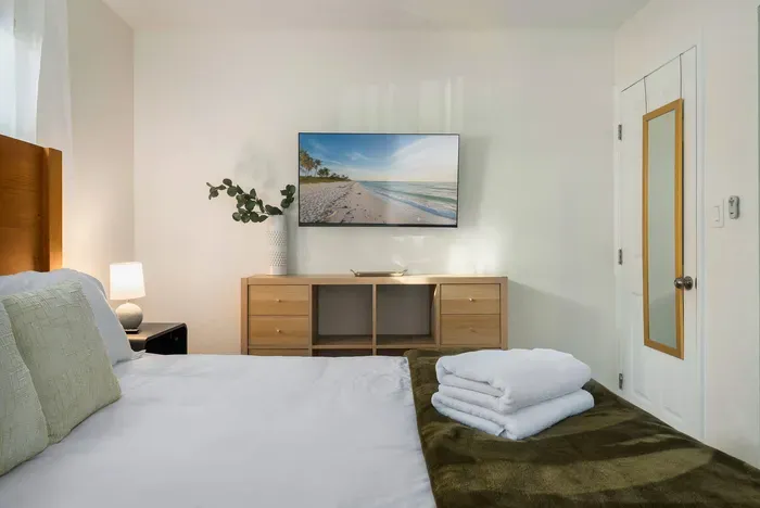 Enjoy this cozy, well-appointed bedroom with a wall-mounted TV, plush bedding, and calming décor. Perfect for unwinding, streaming your favorites, and settling into a restful night’s sleep.