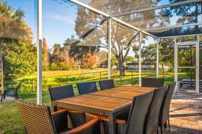 Dine outdoors at the spacious patio table, set within a screened enclosure and overlooking peaceful green views. Perfect for family meals, morning coffee, or evening gatherings in a relaxing, open-air setting.