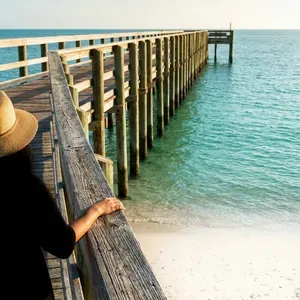Woman in hat on wooden pier overlooking turquoise water
