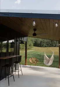 Relax on the outdoor patio featuring a swing chair, fire pit, lounger, wicker chair, and live edge wood countertop and barstools