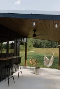 Relax on the outdoor patio featuring a swing chair, fire pit, lounger, wicker chair, and live edge wood countertop and barstools