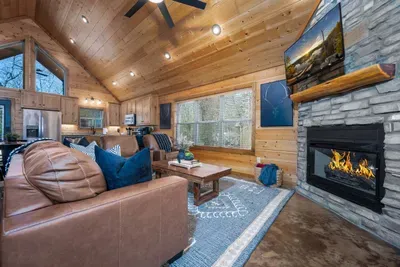 Living Room: Stylish space with plush leather seating, pull out couch to bed,  a stone fireplace, and scenic views.