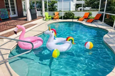 Sunny screened pool with floats, loungers, grill & yard games