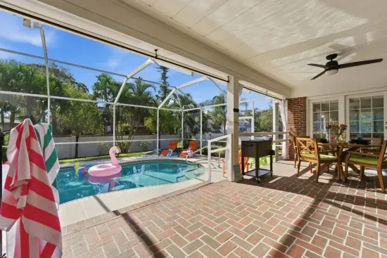 Relax under the covered patio with a view straight to the pool, ceiling fan spinning overhead.
