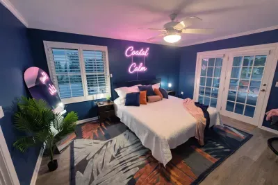 Chic coastal bedroom with neon vibe, French doors, and serene blue tones.