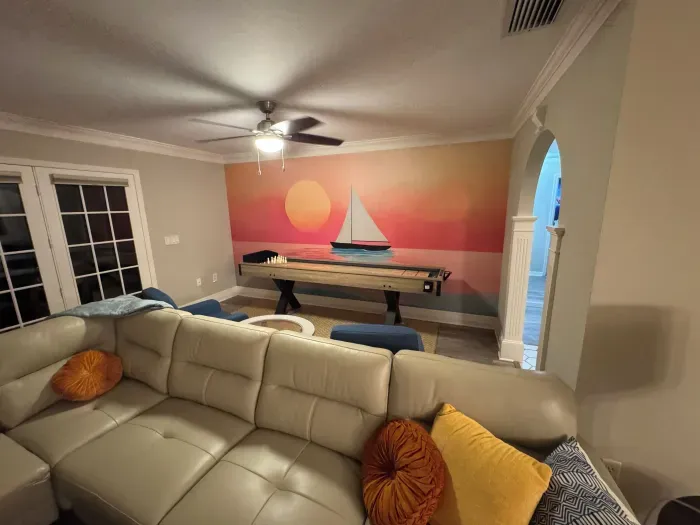 Coastal living room with sailboat mural, sectional and sunset hues