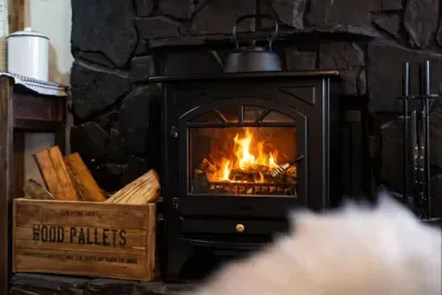 A crackling fire glows inside this electric stove, casting warm light across stone walls and stacked firewood. This inviting hearth creates the perfect cozy atmosphere for relaxing evenings, winter getaways, and unwinding after a day of adventure.