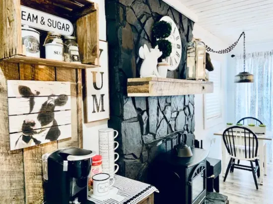 Cozy farmhouse nook with coffee bar, stone hearth, and sunny dining.