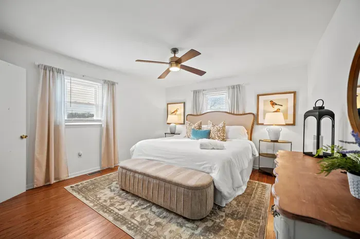 Serene primary suite with king bed, ceiling fan, and sunny windows