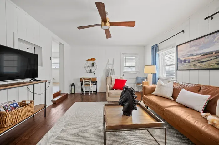 Bright lounge with leather sofa, TV, desk nook & hardwood floors