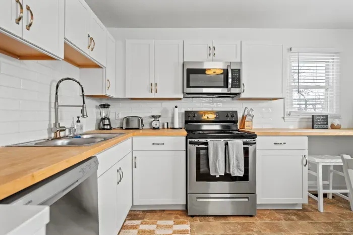 Bright modern kitchen with stainless appliances, butcher-block counters, and a cozy window bar.