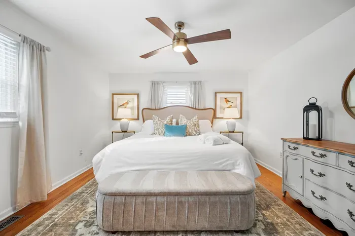 Serene king bedroom with natural light, ceiling fan & vintage charm