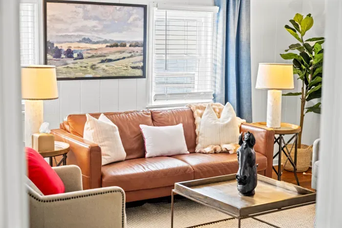 Sunny lounge with leather sofa, chic decor, and cozy, well-lit seating.